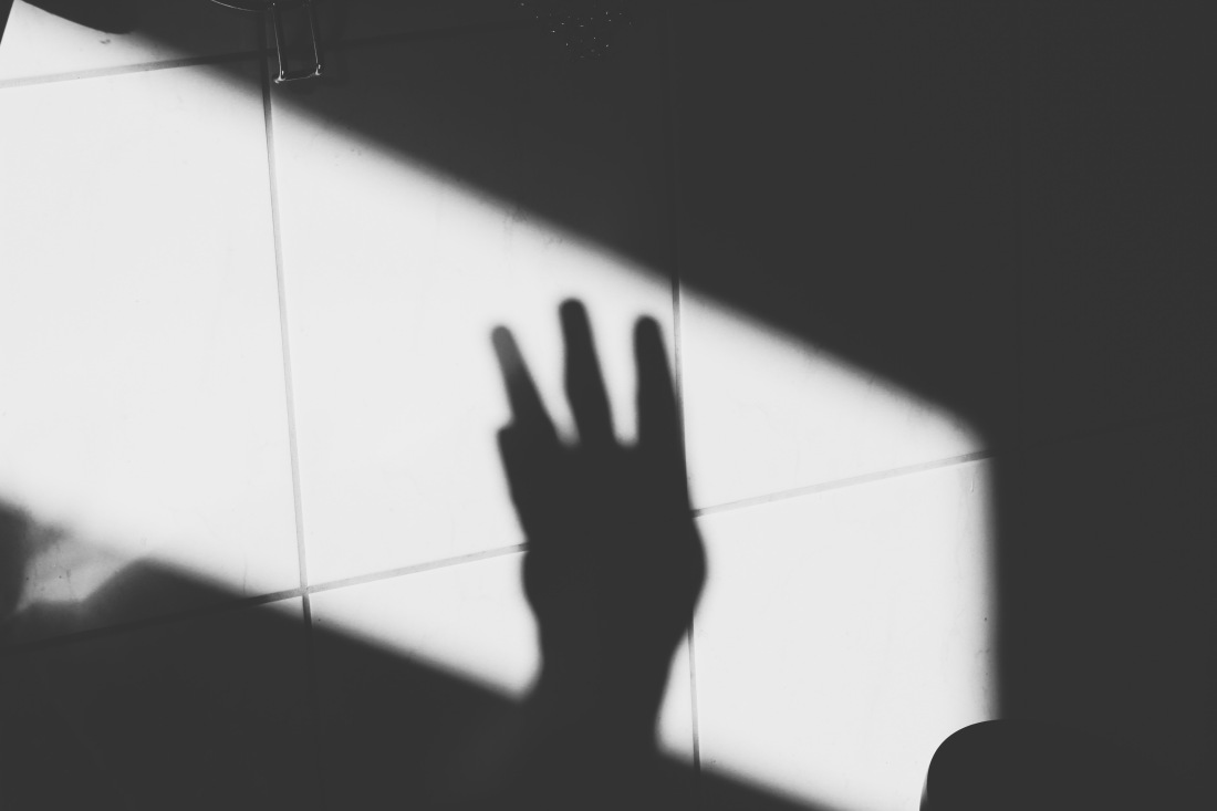 Schwarz-weiß Bild, Schatten einer Hand auf Fliesen.